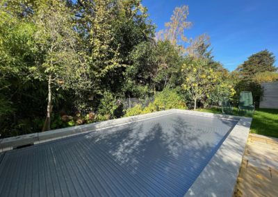 Réalisation d'une piscine avec carrelage blanc - nage contre-courant - volet solaire et margelles en béton brut