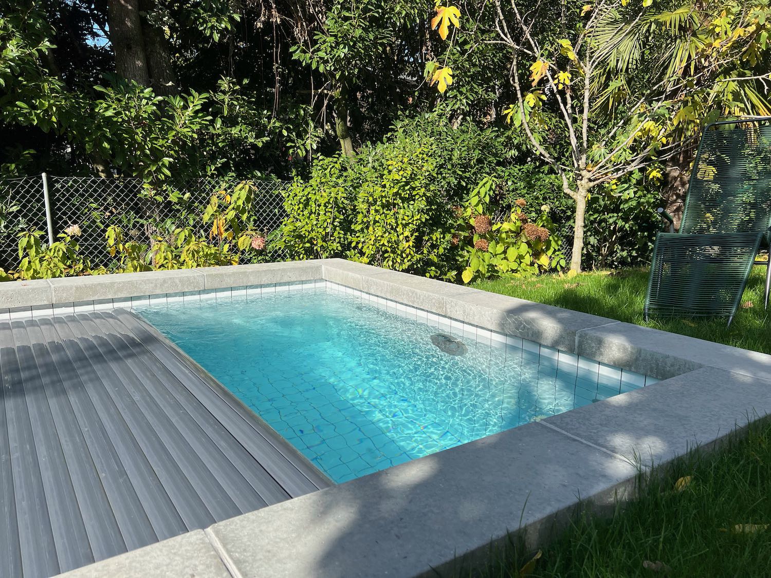 Réalisation d'une piscine avec carrelage blanc - nage contre-courant - volet solaire et margelles en béton brut