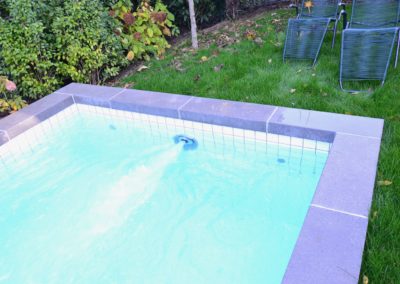 Réalisation d'une piscine avec carrelage blanc - nage contre-courant - volet solaire et margelles en béton brut