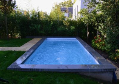 Réalisation d'une piscine avec carrelage blanc - nage contre-courant - volet solaire et margelles en béton brut