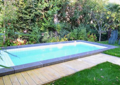 Réalisation d'une piscine avec carrelage blanc - nage contre-courant - volet solaire et margelles en béton brut