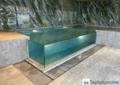 Piscine en verre avec débordement dans un chalet en Valais