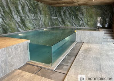 Piscine en verre avec débordement dans un chalet en Valais